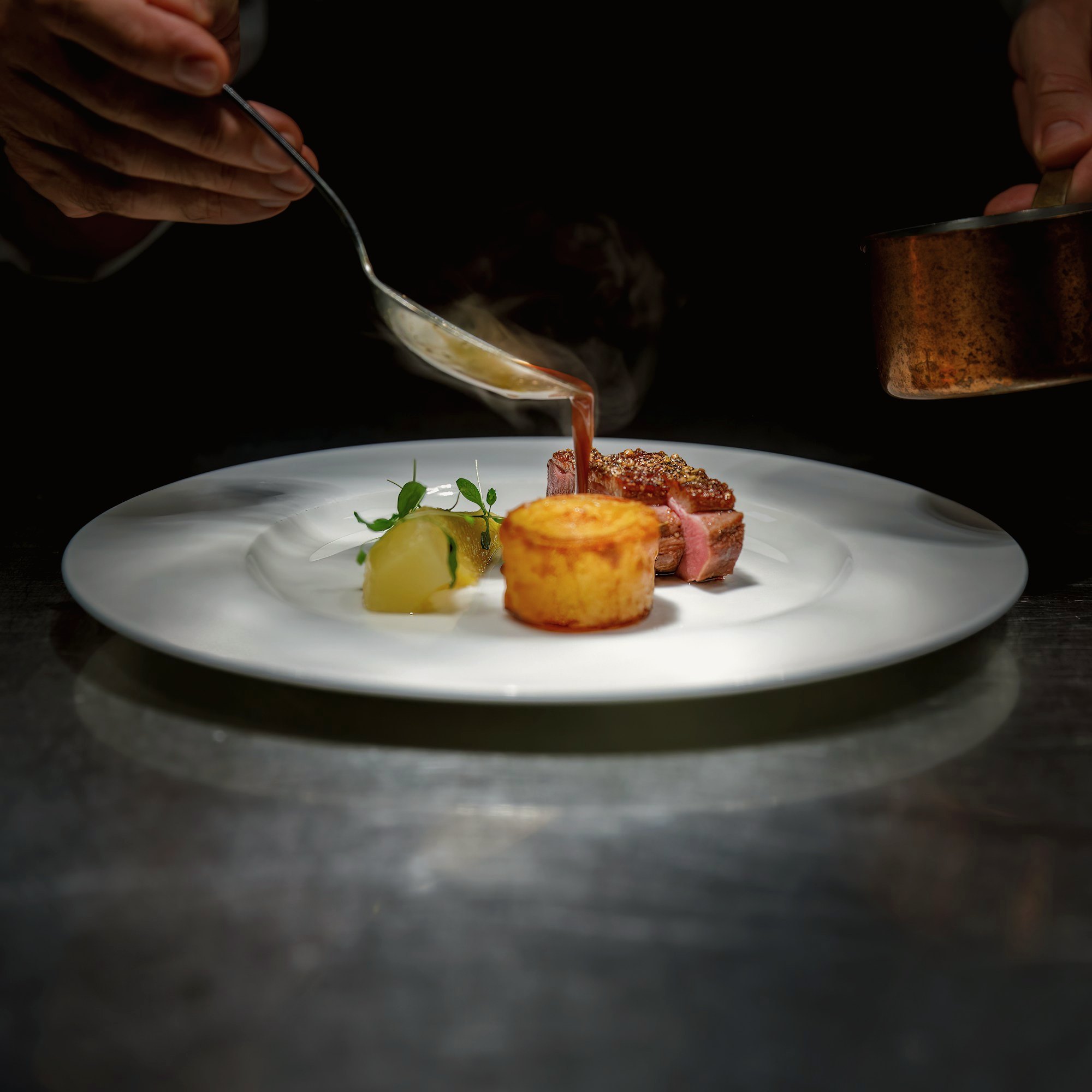 Un chef nappe une assiette de sauce